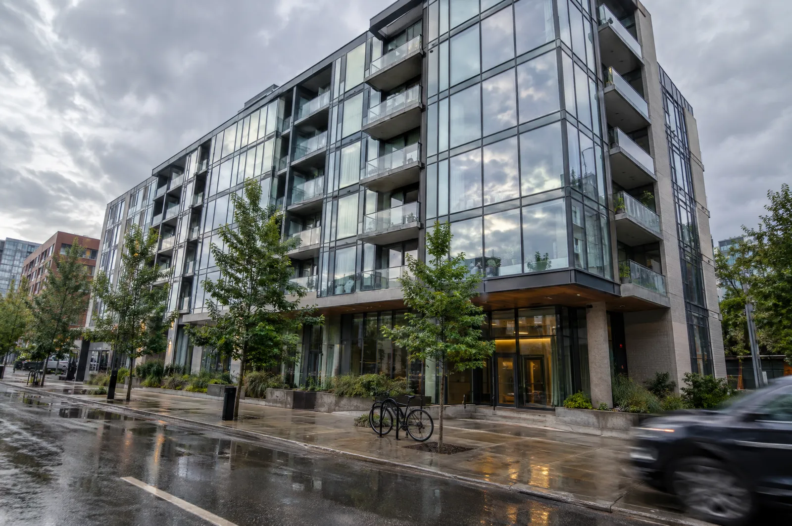 Mid-rise condominium with floor-to-ceiling glazing on a wet city street