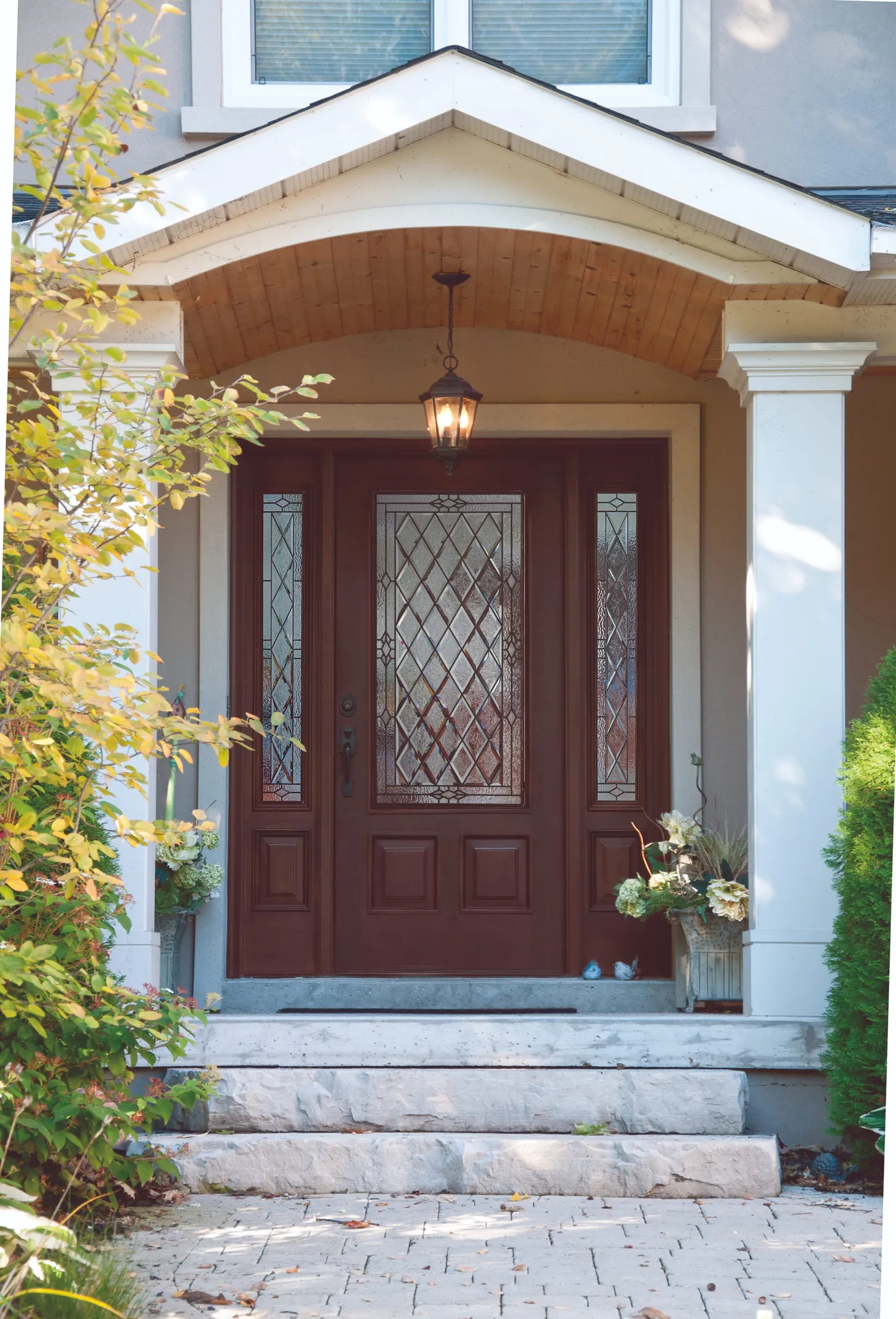 Red entry door with decorative glass and two sidelites under a covered porch