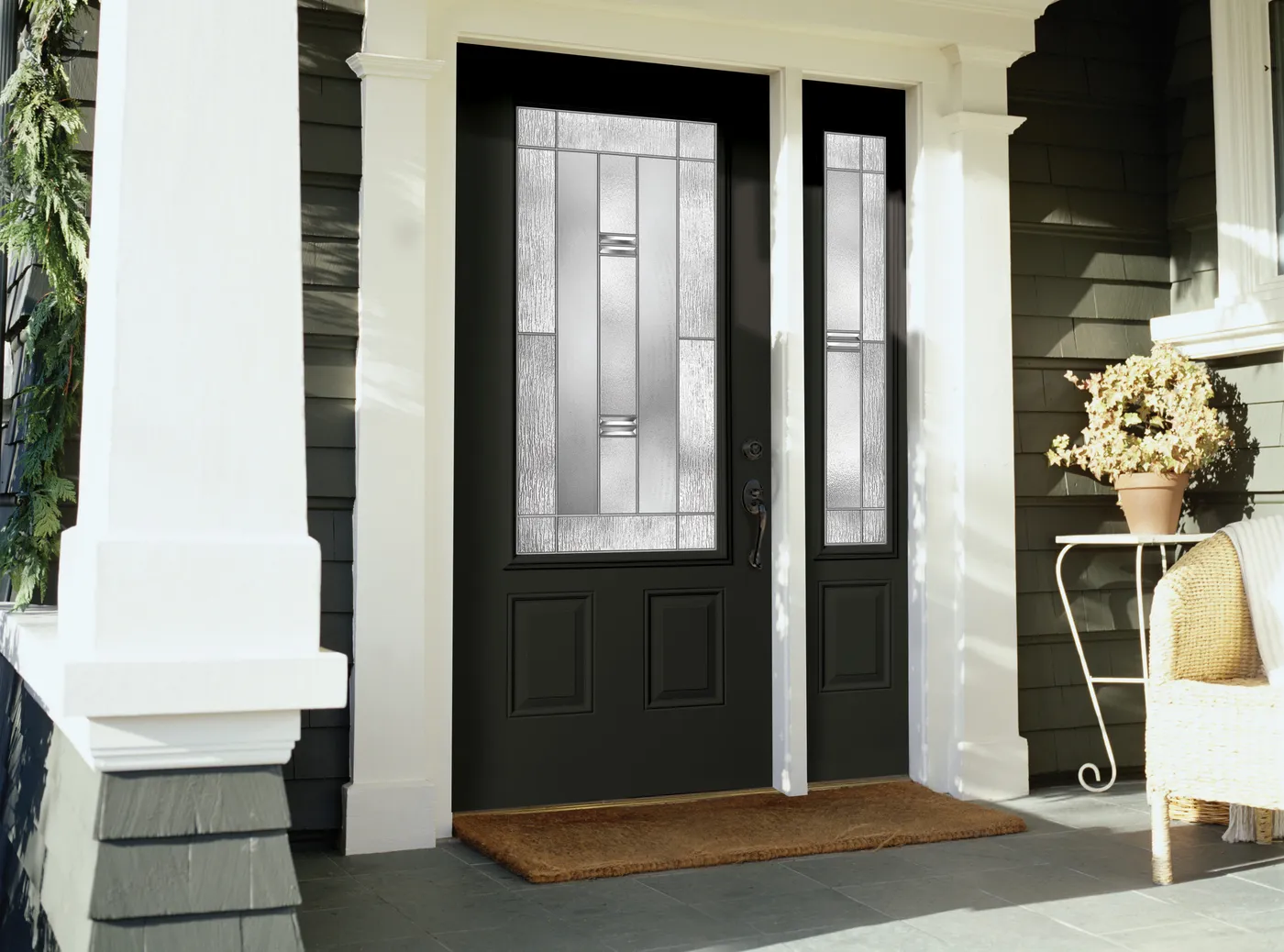 Black entry door with three-quarter decorative glass and a matching sidelite on a porch