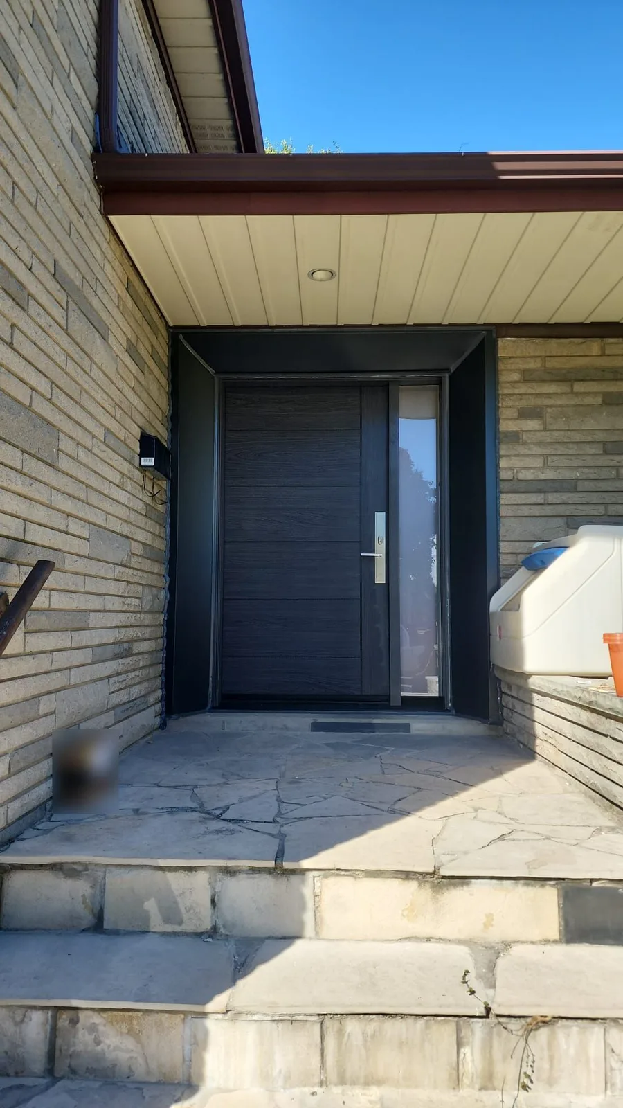 Finished front entrance under a porch, with dark trim wrapped around the opening