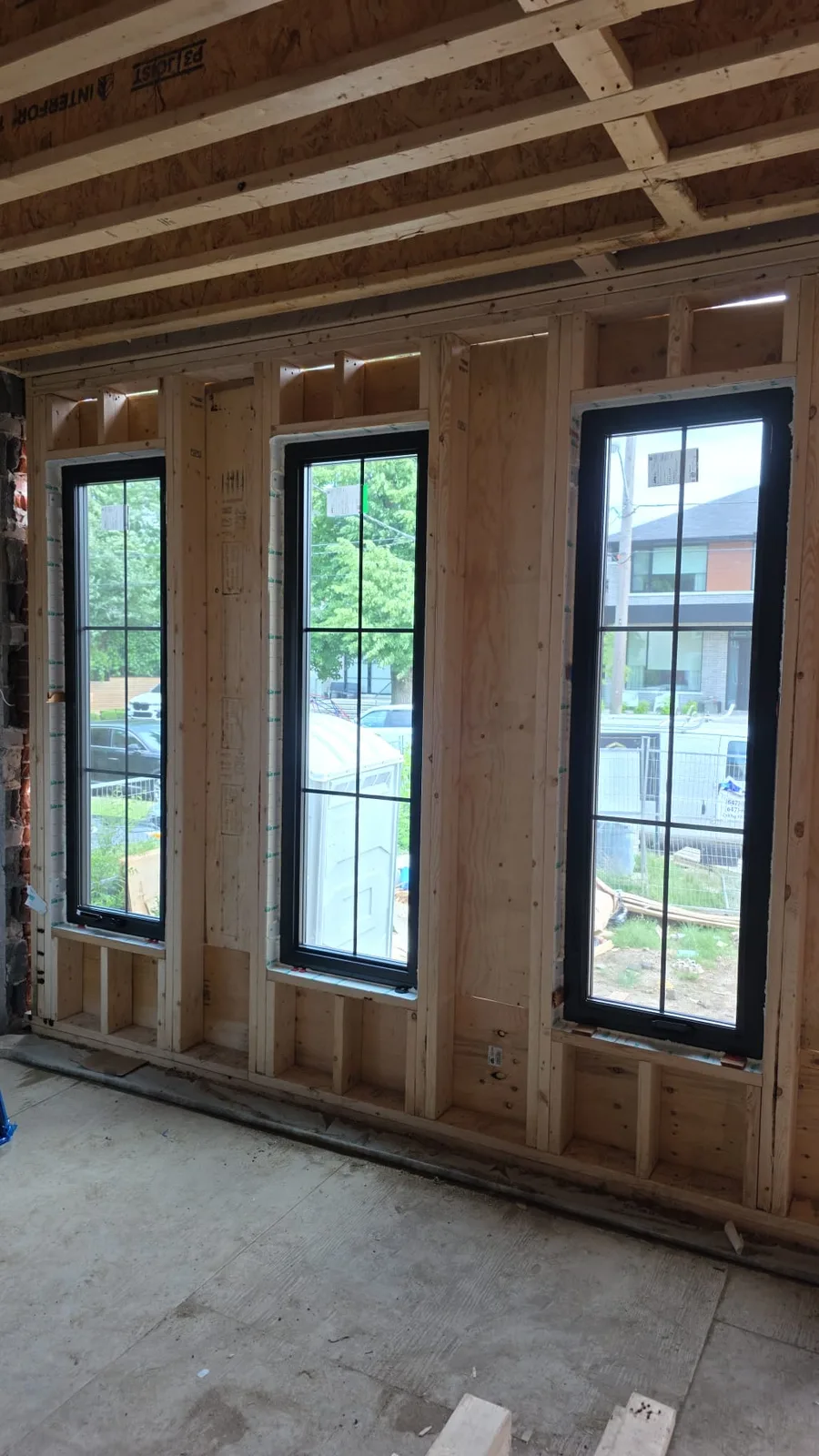 Three tall black windows with grilles installed in new timber framing