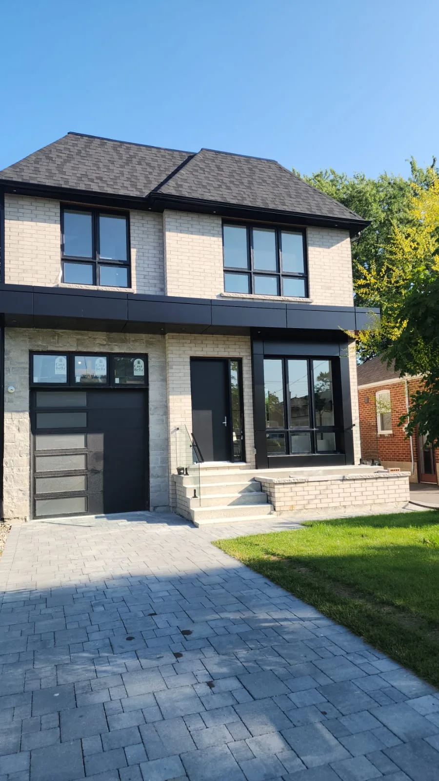 Modern two-storey home with black-framed windows and a black front door with a glass sidelite