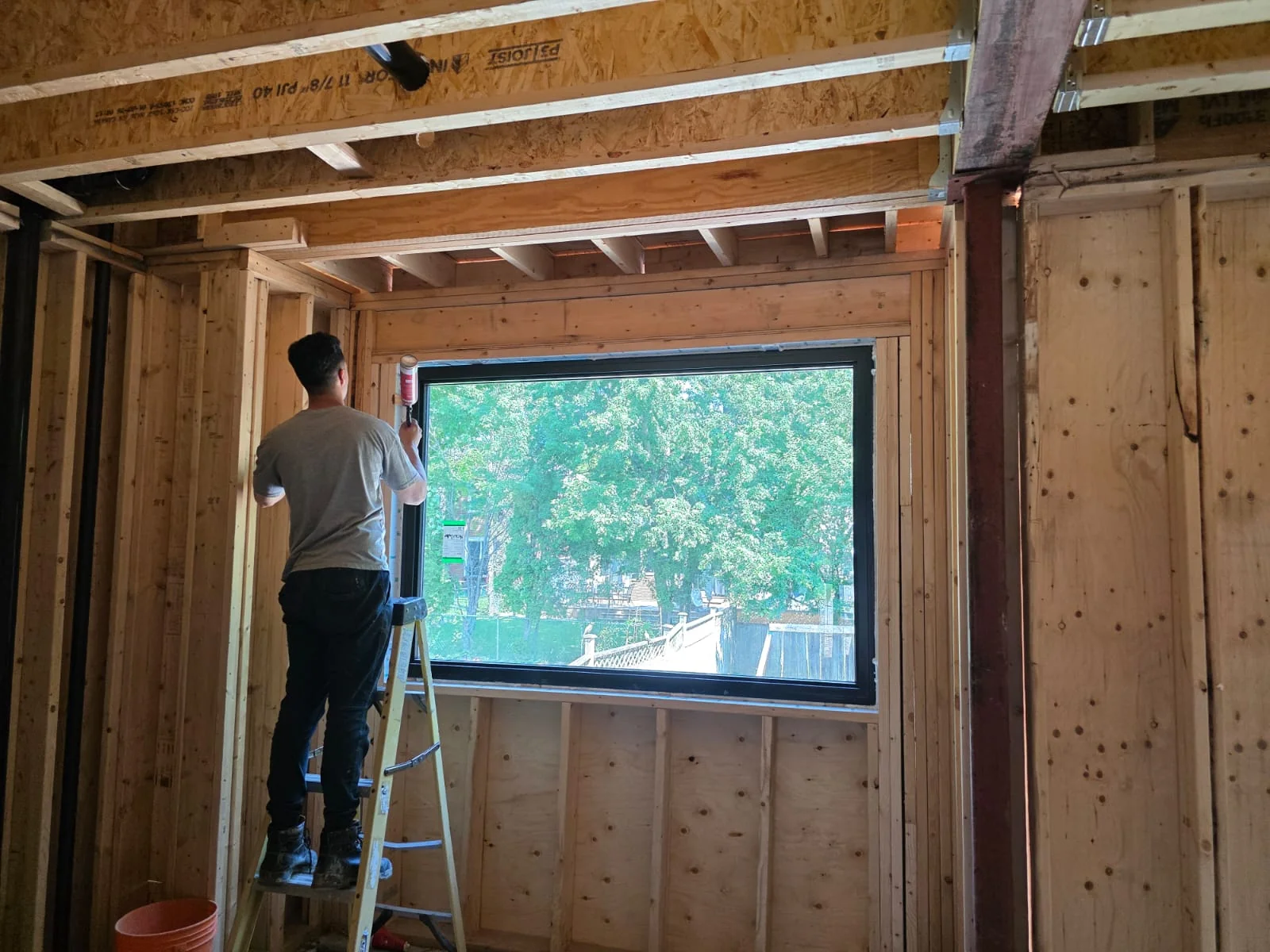 Installer working beside a wide window in a timber-framed room